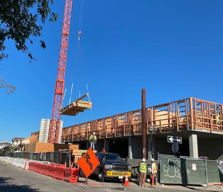 Crane setting panel on multi-story building