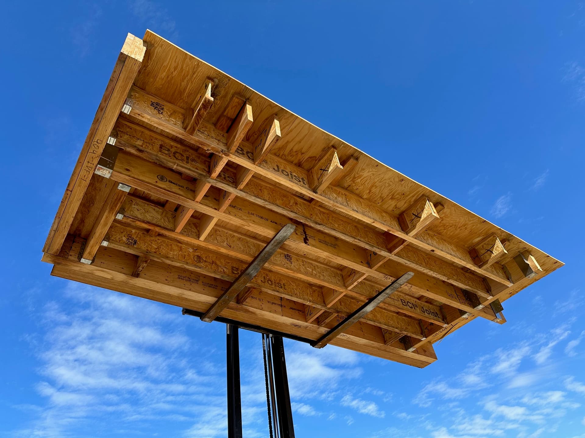 Floor cassette lifted against blue sky showing joist structure