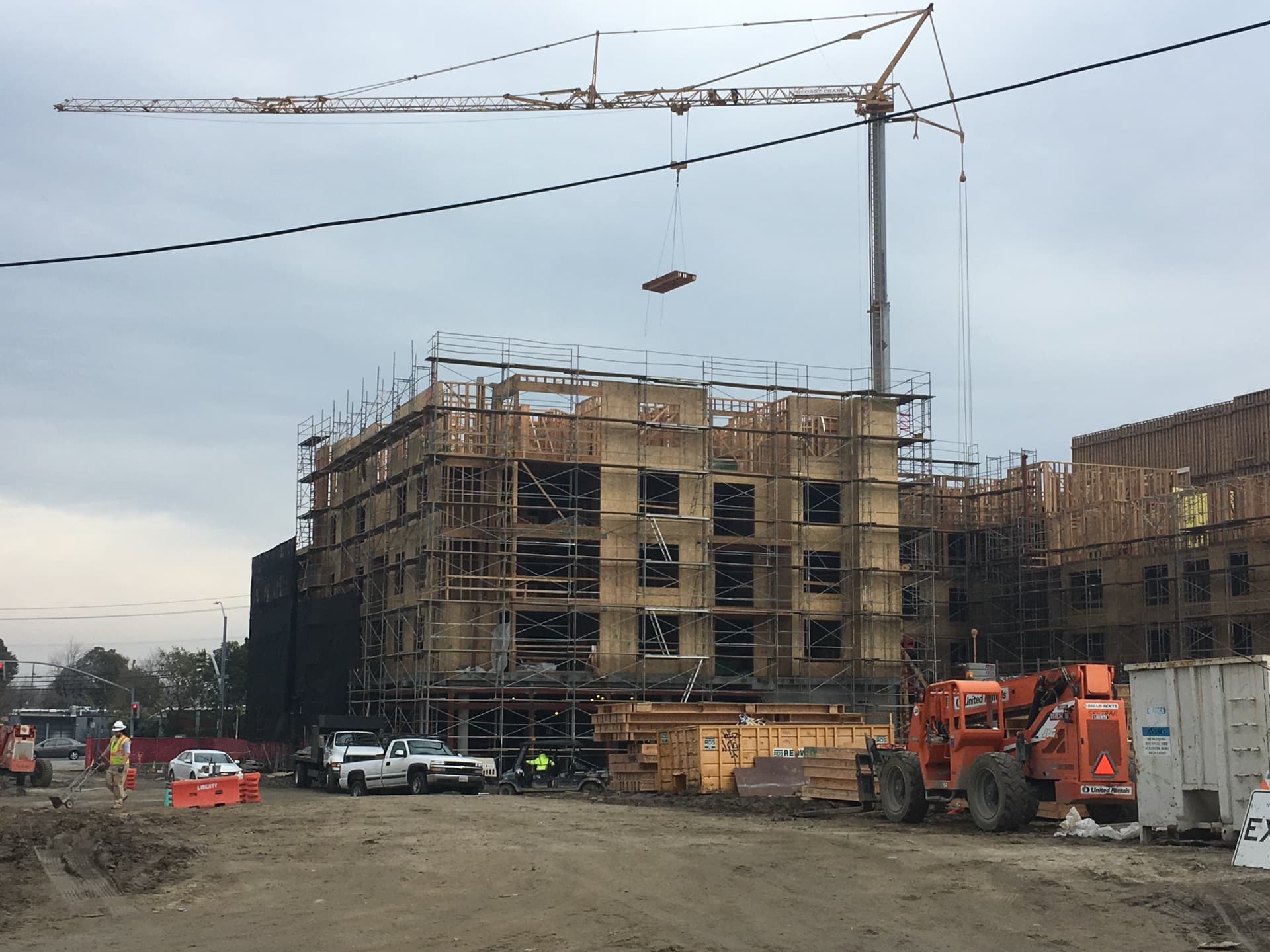 Tower crane lifting floor cassette at multi-story construction site
