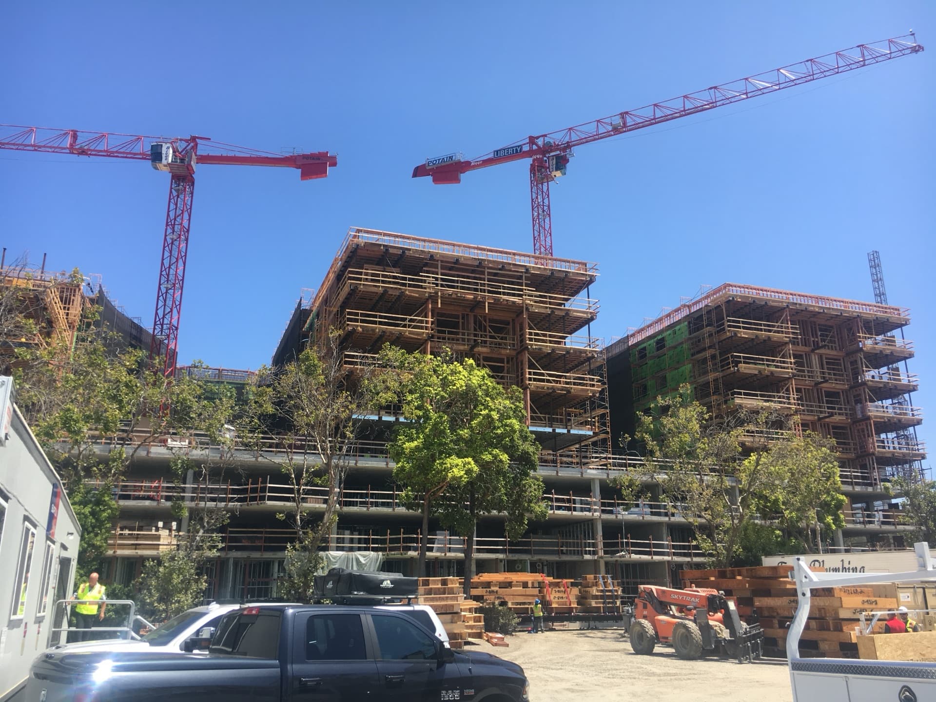 Three red tower cranes over multi-building construction complex